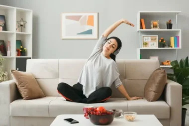 pleased-young-girl-wearing-headphones-doing-yoga-sitting-sofa-coffee-table-living-room daily energy