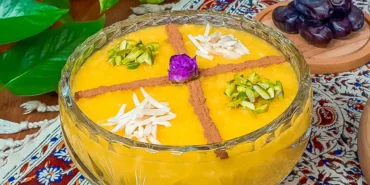 یک ظرف بزرگ شله زرد تزیین شده با دارچین و خلال پسته و خلال بادام و یک غنچه رز گل محمدی در وسط